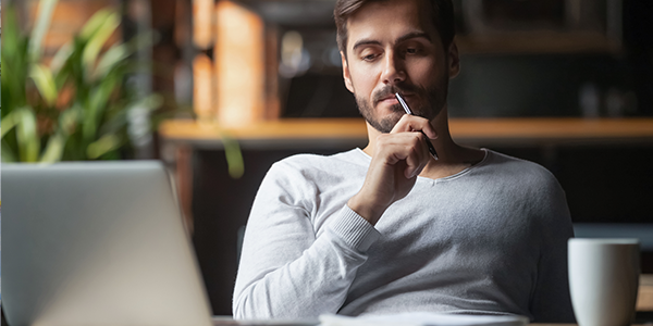 Man working on computer while enjoying a cup of coffee